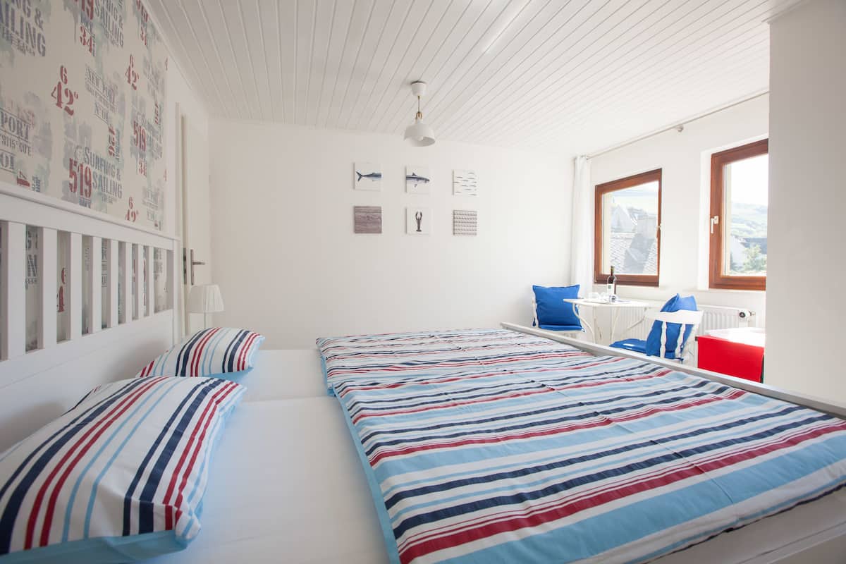 A room with two beds, a desk, and a window.