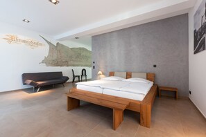 Un dormitorio moderno con una cama grande, un sofá y un mural en la pared.