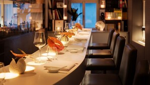 A restaurant with a long table set for dining, bookshelves in the background, and a view of the cityscape through the window. - Bachofer (Waiblingen)