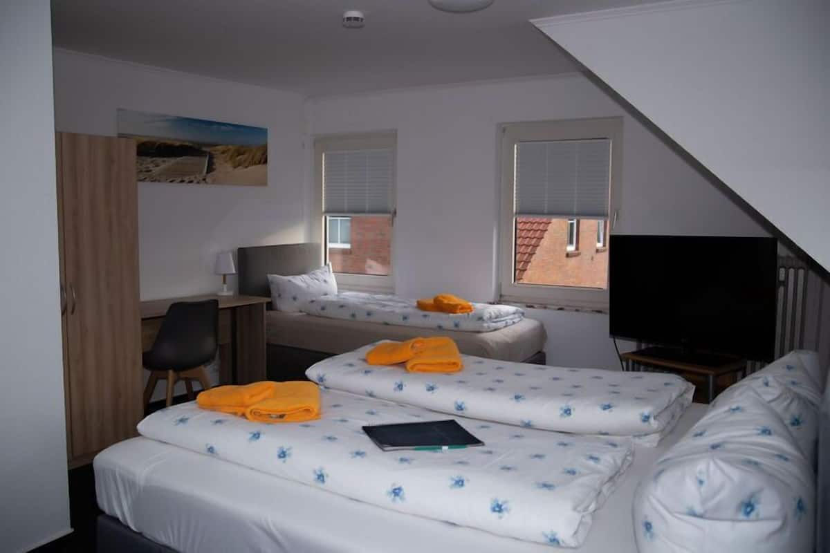 A room with two beds, a desk, a chair, and a television.