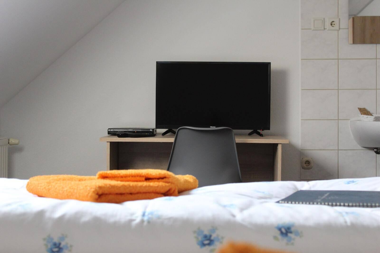 Une chambre d’hôtel avec un lit, un bureau doté d’une télévision et une chaise.