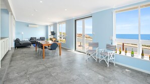 A spacious room with a dining area, a sofa, and a view of the sea.
