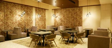 A modern lounge area with multiple seating options, including tables and chairs, and decorative wall panels.