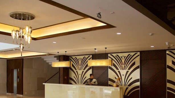 Eine moderne Hotelhalle mit einer Rezeption, einer Kristallleuchtre und einer Sitzecke mit weißen Sofas.