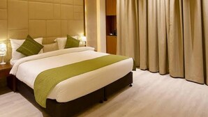 Ein modernes Hotelzimmer mit einem großen Bett, einem Deckenventilator und Blick ins Freie durch Vorhänge.