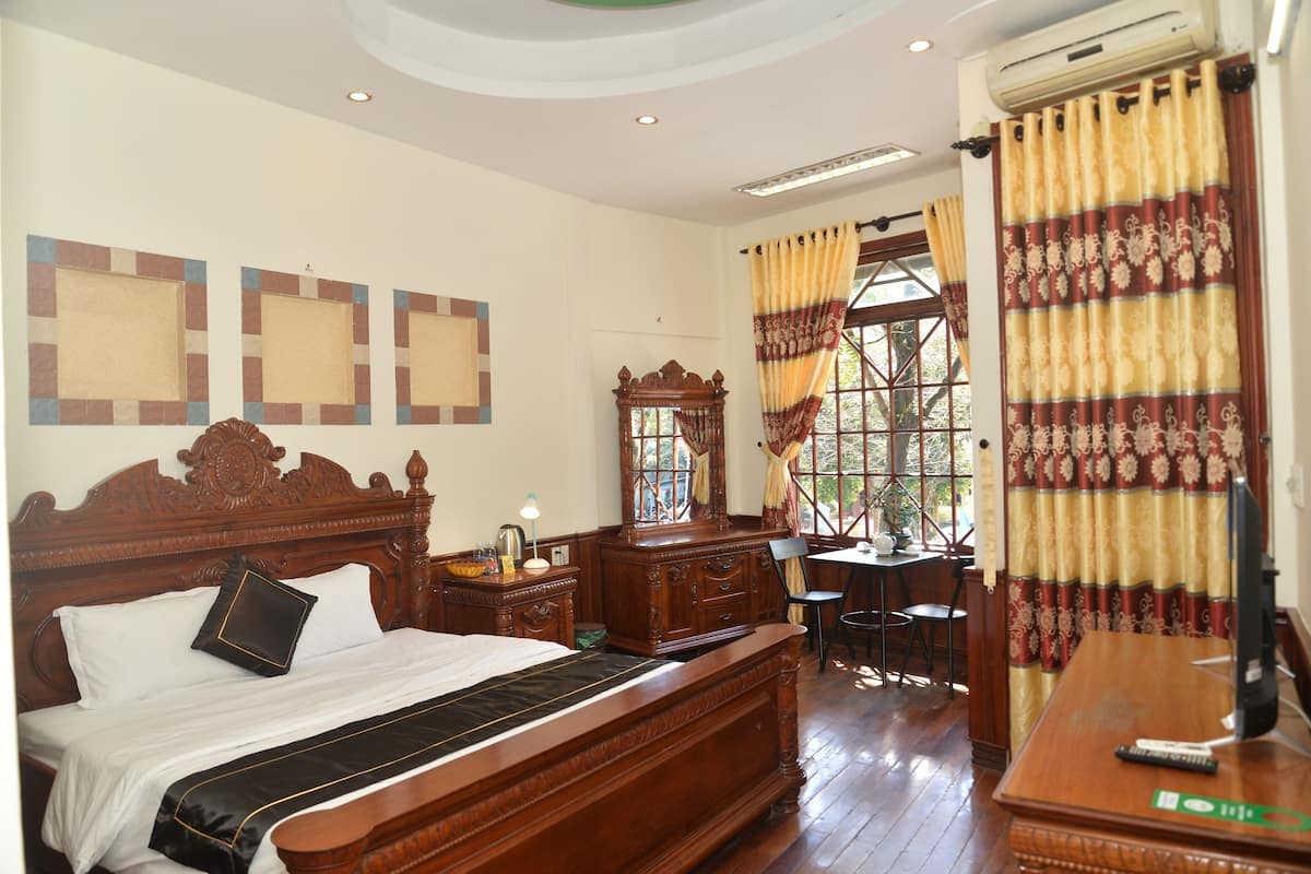 A traditional bedroom with a wooden bed, a desk, and a chair.