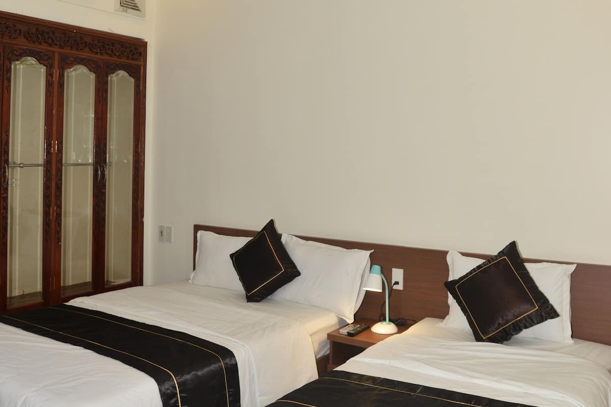 A hotel room with two beds, a ceiling fan, an air conditioning unit, and a wooden wardrobe.