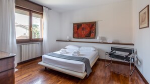 A neatly arranged bedroom with a bed, bedside table, and a chair.
