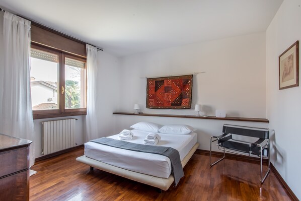 A neatly arranged bedroom with a bed, bedside table, and a chair. - Padova - Via Rizzo 49A (Padova)