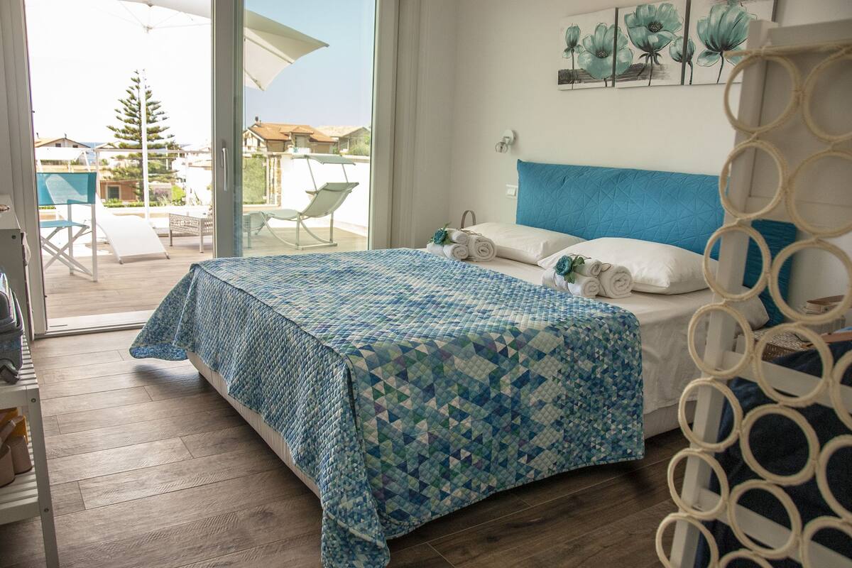 A bedroom with a bed, a view of the outside, and a window.