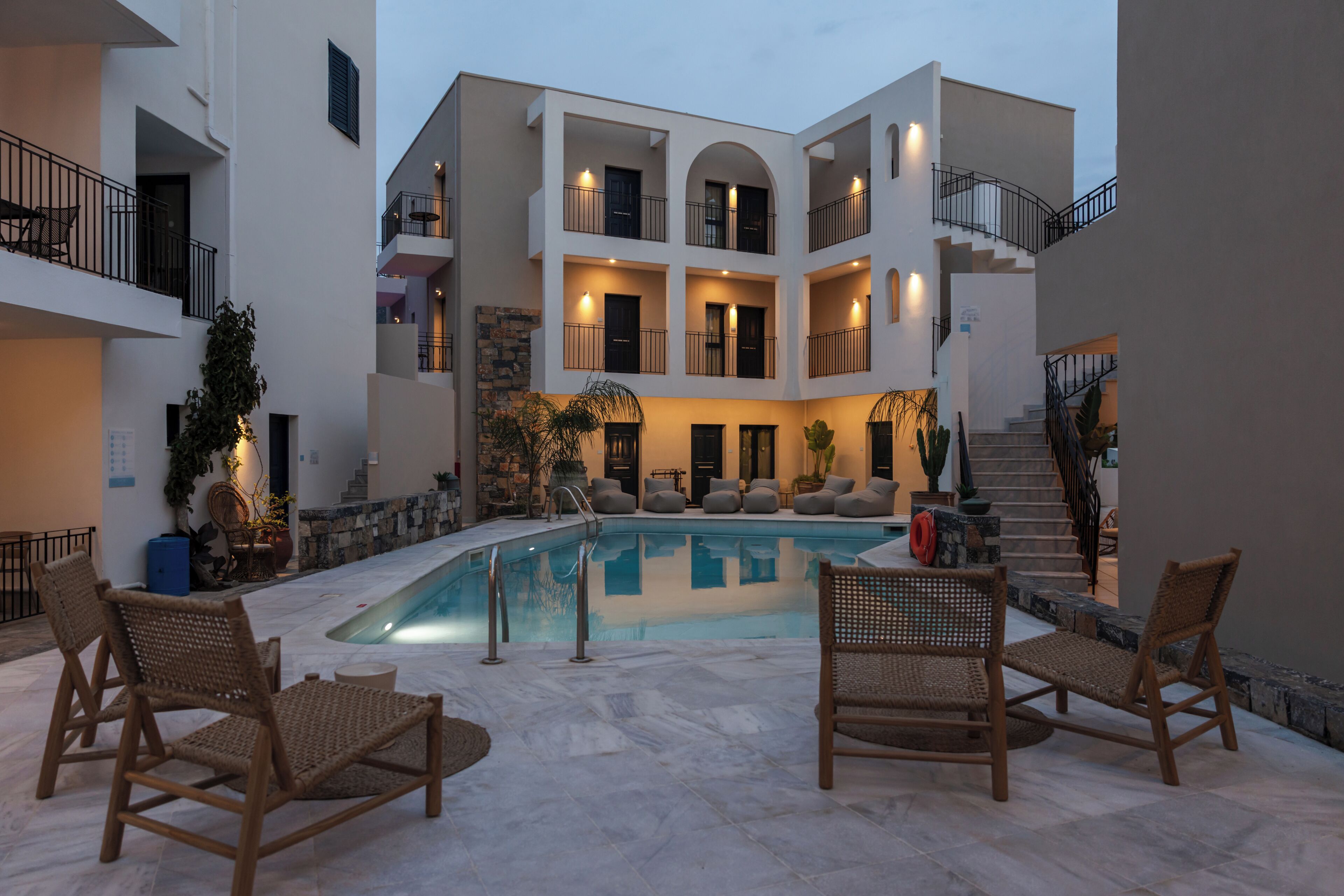 A multi-story building with a swimming pool, outdoor seating, and a staircase.