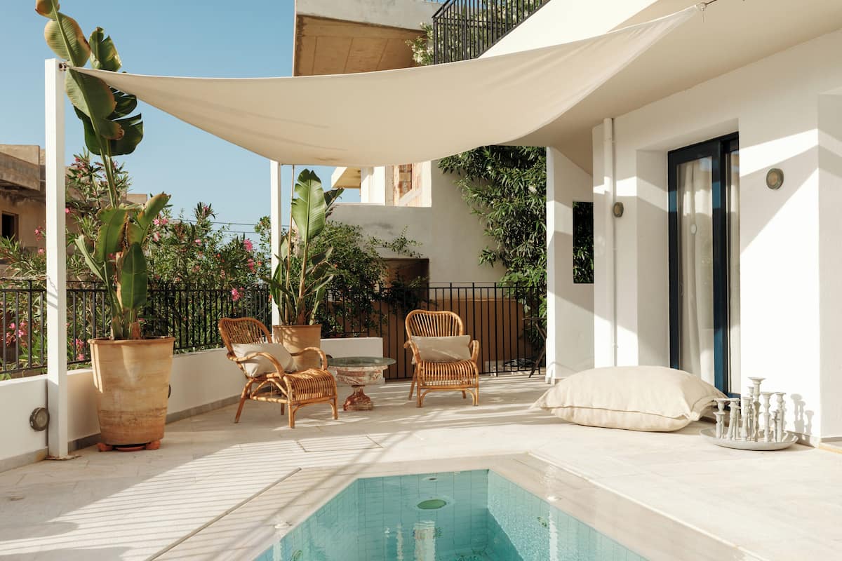 Zona de piscina en la azotea con piscina, sillas de descanso, plantas en macetas y una pérgola.