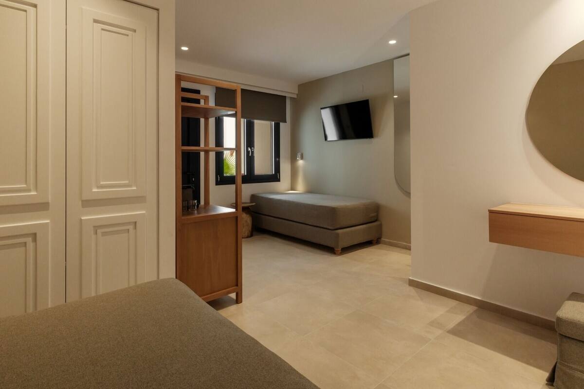 Un dormitorio moderno con un armario grande, una mesita de noche y un espejo redondo.