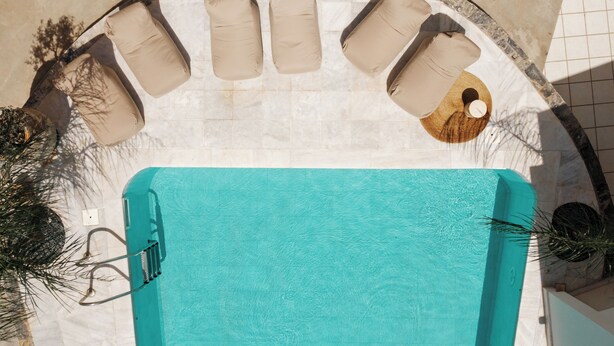 A top-down view of a swimming pool with six beige lounge chairs and a wooden deck. - Nami Hotel & Suites (Hersonissos)