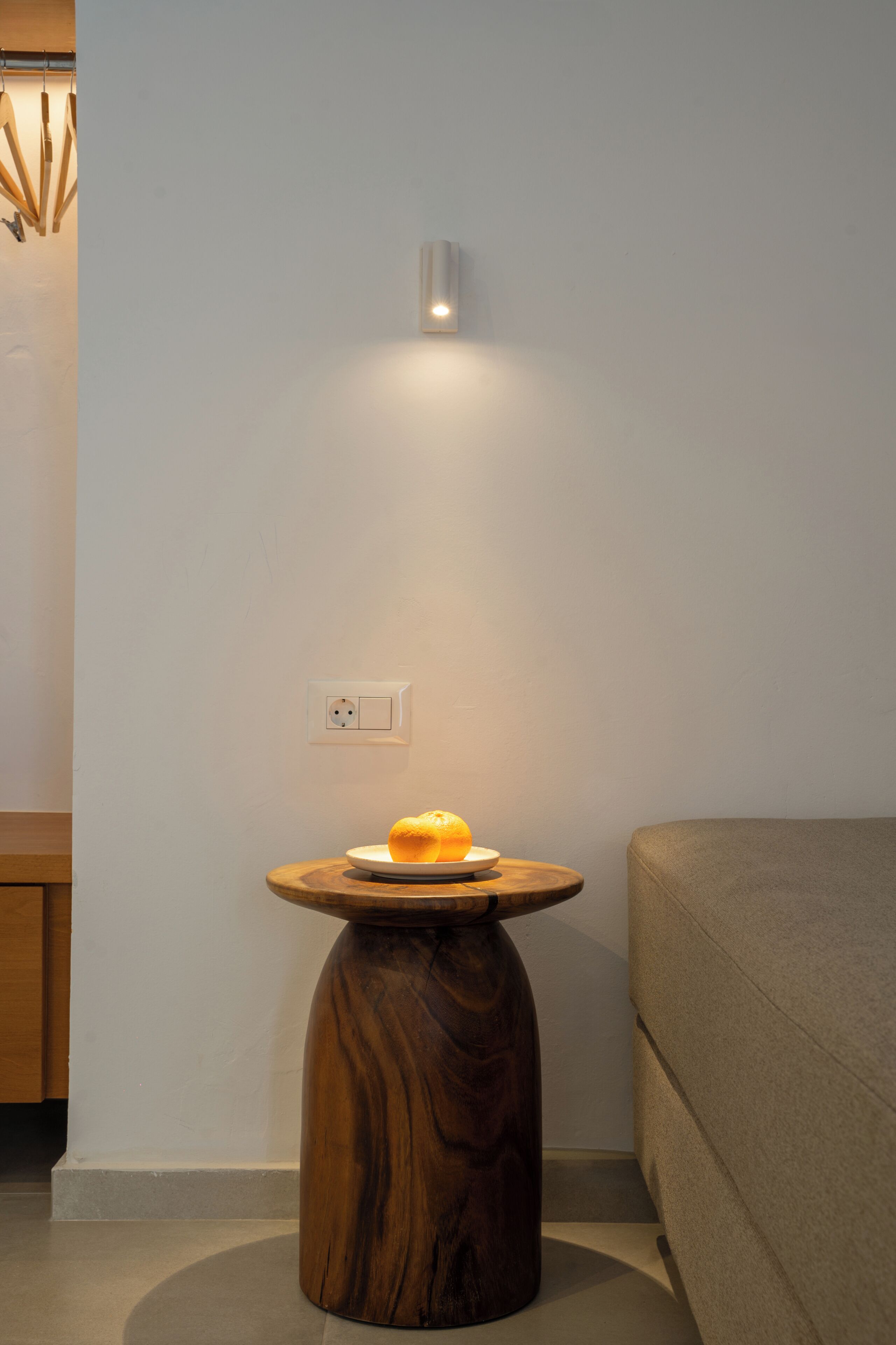 Une pièce moderne avec une table ronde en bois, une seule orange et un luminaire fixé au mur.