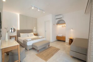 Une chambre à coucher moderne comprenant un lit, des tables de chevet, un bureau, un banc, un canapé et un appareil de climatisation.