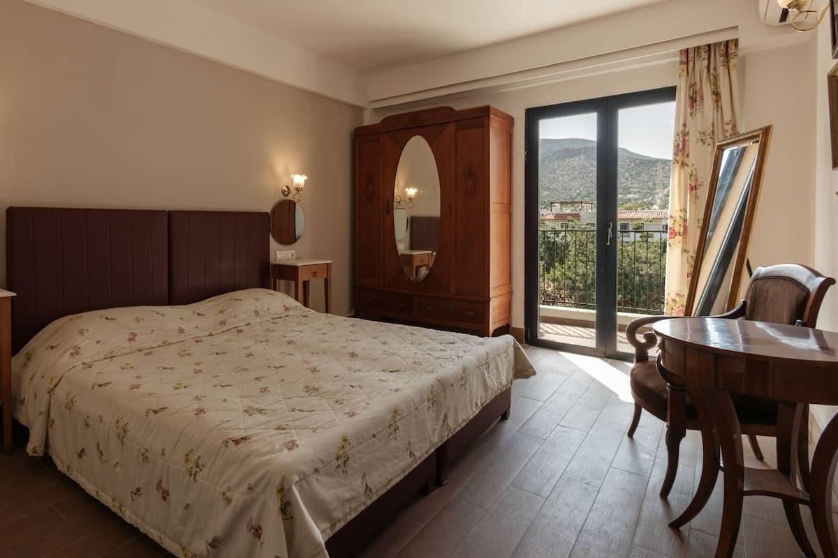 Un dormitorio con cama, mesitas de noche, armario, escritorio y balcón con vistas.