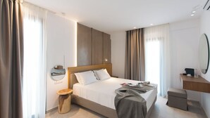 A modern hotel room with a large bed, bedside table, and a small desk with a mirror. - Nami Hotel & Suites (Hersonissos)