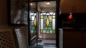 Una cocina moderna con un ventanal grande, una silla con cojín verde y un armario de madera.