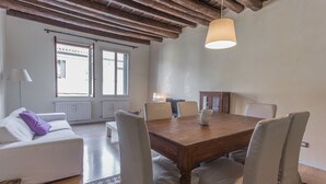 A dining area with a wooden table, four chairs, a white sofa, and a lamp. - Padova - Via Tadi 39 (Padova)