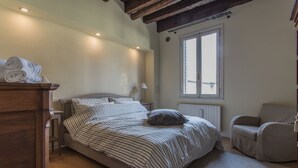 A bedroom with a bed, a chair, a radiator, and a window. - Padova - Via Tadi 39 (Padova)