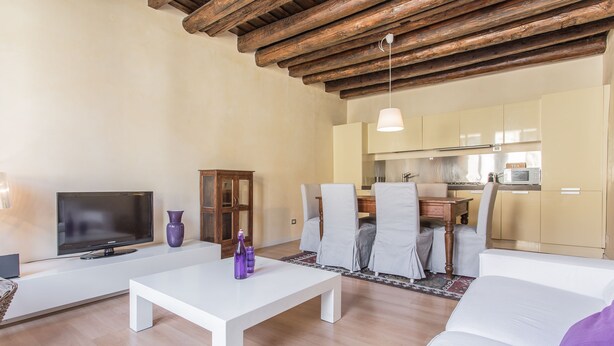 A modern living room with a flat-screen TV, white sofas, a coffee table, and a kitchen in the background. - Padova - Via Tadi 39 (Padova)