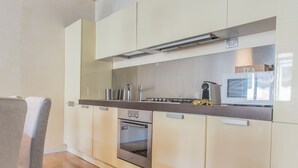 A modern kitchen with wooden beams, stainless steel appliances, and light-colored cabinetry. - Padova - Via Tadi 39 (Padova)