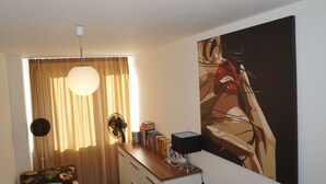 Een kamer met een houten bureau, een lamp, een groot schilderij en een raam met gordijnen.