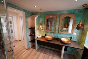 A bathroom with a large mirror, two sinks, and decorative vases.