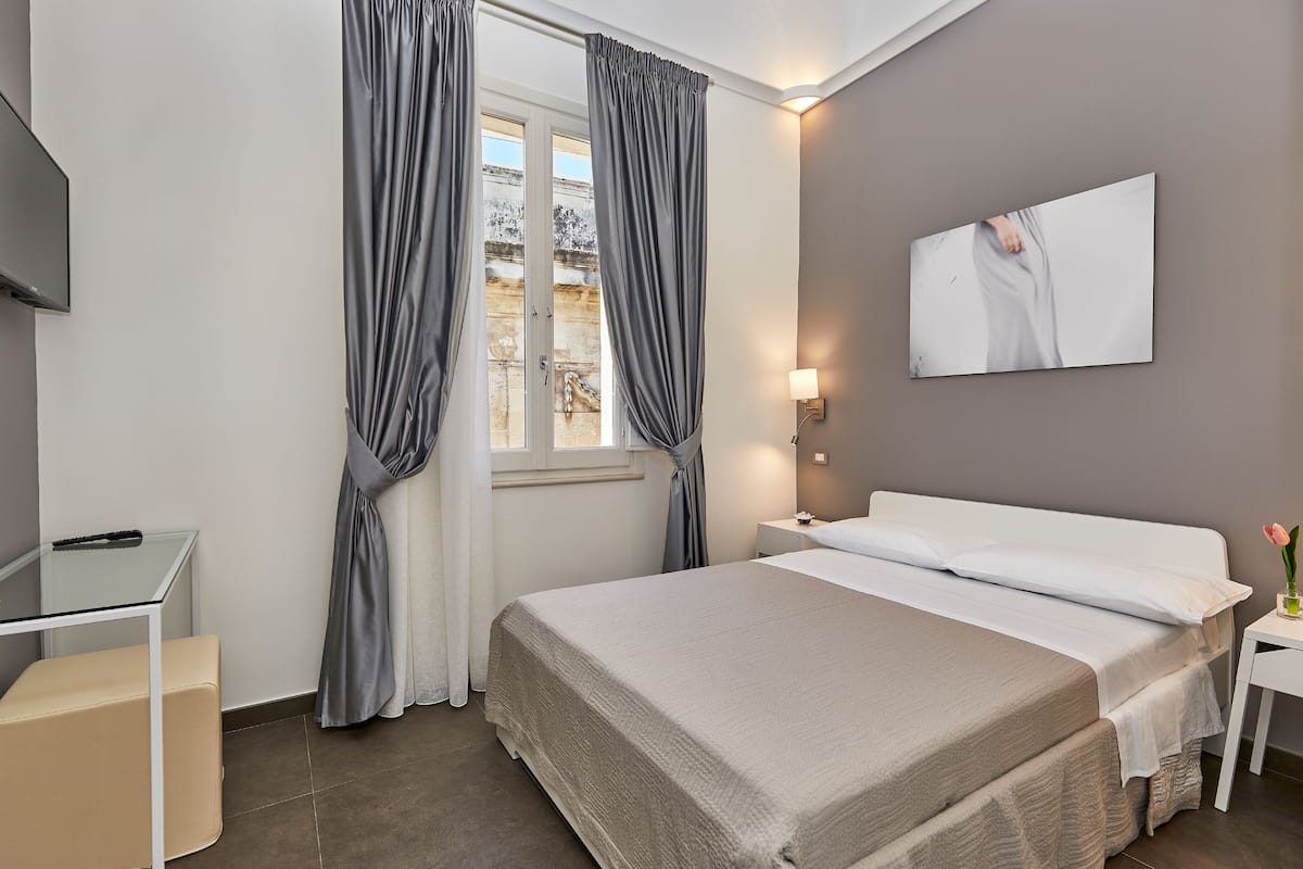 Ein Schlafzimmer mit Bett, Schreibtisch und Fernseher an der Wand.