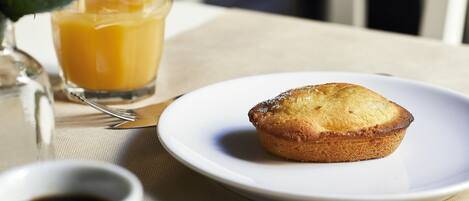 Café da manhã com um muffin em um prato, um copo de suco de laranja e uma xícara de café.