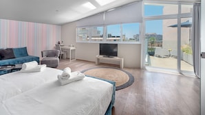 Una habitación de hotel moderna con una cama grande, un escritorio, televisión y un balcón con vistas a la ciudad.