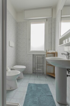 A modern bathroom with a toilet, bidet, and sink.