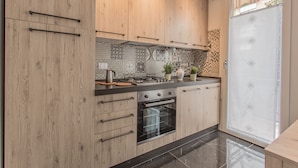 A modern kitchen with wooden cabinets, a built-in oven, and a black countertop. - Padova - Pierobon 18 (Padova)