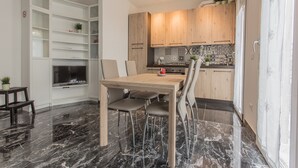 A modern kitchen with wooden cabinets, a marble floor, and a dining area with a table and chairs. - Padova - Pierobon 18 (Padova)