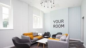 A modern living room with a grey sofa, a black armchair, and a white coffee table. - Popup Durham (Durham)