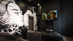 A modern lounge area with a large mural, comfortable seating, and a flat-screen TV. - Popup Durham (Durham)