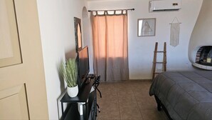 A bedroom with a bed, a TV, a small table with a plant, a ladder, and a fireplace. - SPECIALS! Pet Friendly, Beach Bungalow, Peaceful, Private, 2 Bedroom, 2 Bath! (Puerto Penasco)