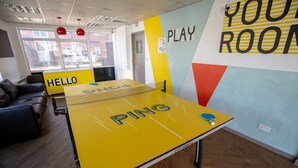 A ping pong table in a room with a 'Hello' sign, a 'Your Room' sign, and a window with a view of buildings. - Popup Liverpool (Liverpool)