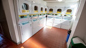 A laundry facility with multiple washing machines and dryers, a tiled floor, and a trash bin. - Popup Liverpool (Liverpool)
