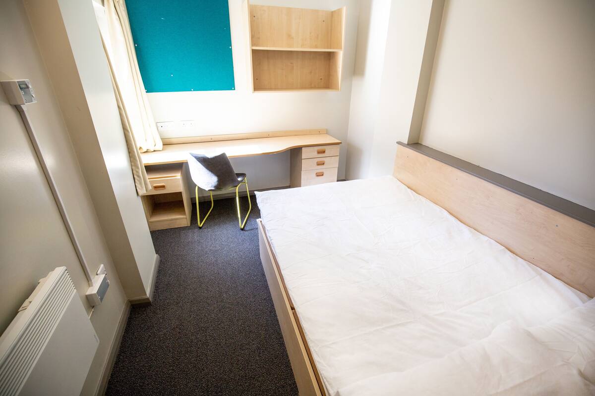 A bedroom with a bed, a desk, and a chair.