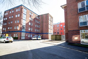 A multi-story brick building with a flat roof and large windows. There are two cars parked in front of the building. - Popup Liverpool (Liverpool)