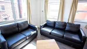 Two black leather sofas, a wooden coffee table, and large windows with curtains. - Popup Liverpool (Liverpool)