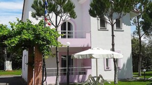 A two-story building with a white facade, a balcony, and a flagpole with multiple flags. - Chroma Studios (Istiaia-Aidipsos)