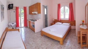 A bedroom with a wooden bed, a small bedside table, a nightstand, a window with curtains, and a view of the outside. - Chroma Studios (Istiaia-Aidipsos)