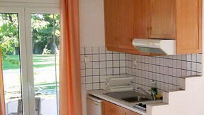 A compact kitchen with wooden cabinets, a tiled backsplash, and a built-in oven. - Chroma Studios (Istiaia-Aidipsos)