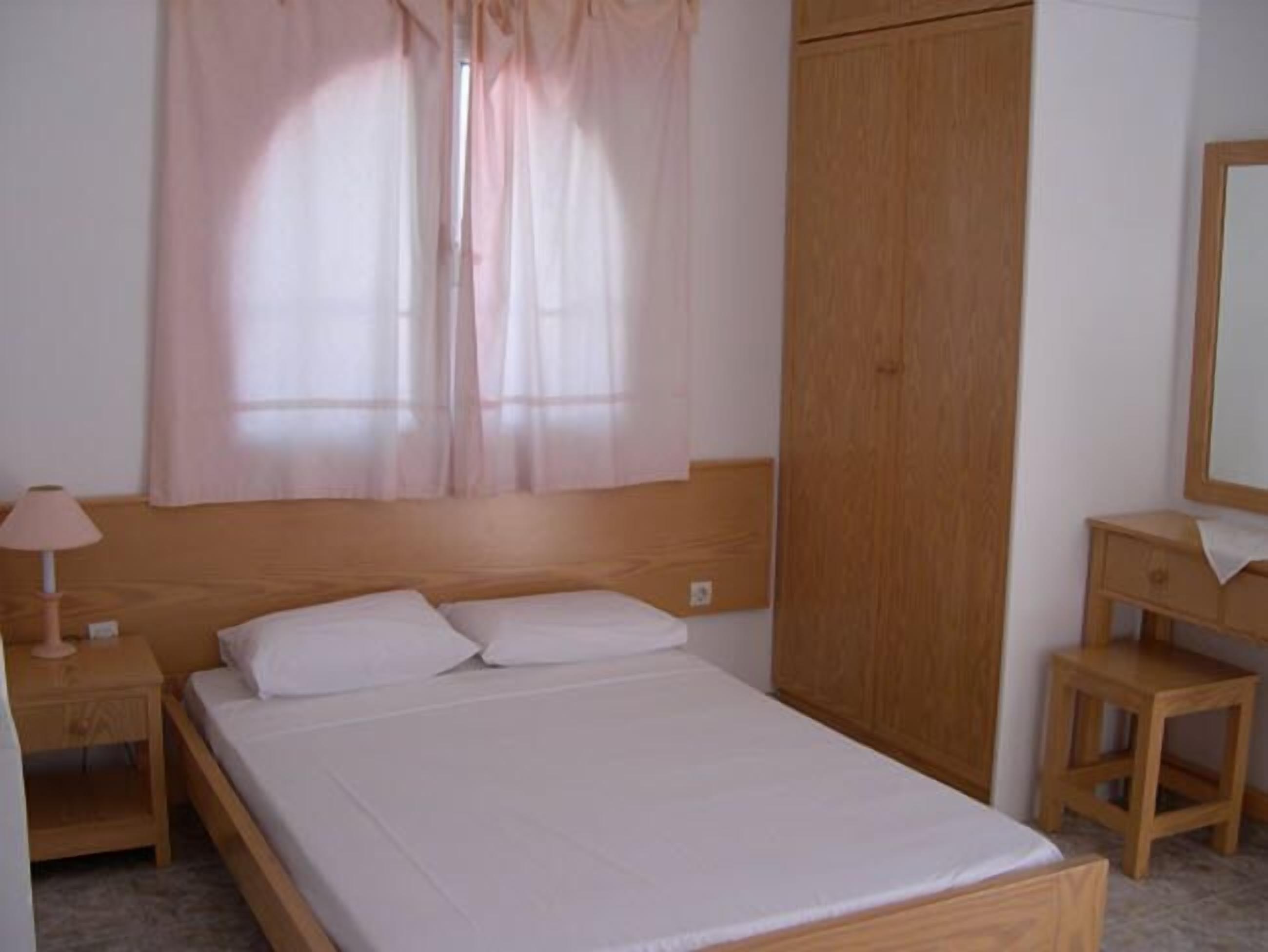 Un dormitorio con una cama de madera, una mesita de noche, un armario de madera y un espejo.