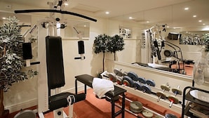 Une salle de sport équipée de matériel d’exercice, d’un banc, de poids et d’un miroir.