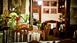 Un comedor con sillas y mesas de madera, un florero con flores y cuadros en la pared.