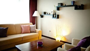 Una sala de estar con sofá, una mesa de centro, una lámpara y estanterías con objetos decorativos.
